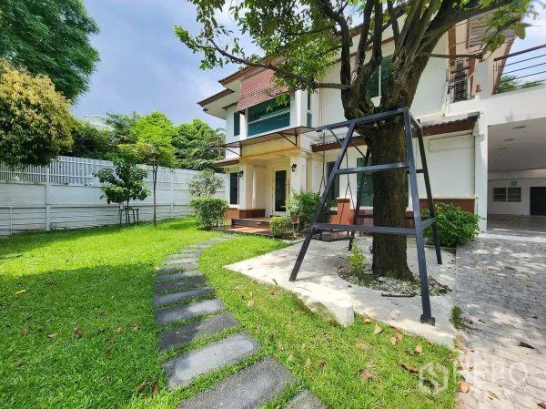 Detached House for rent in Bang Kapi, Bangkok - Close view of the landscaped front garden with stepping-stone path and a swing under a large tree.