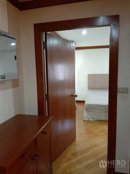 Apartment for rent in Watthana, Bangkok - Hallway view toward a bedroom with wooden cabinetry and door.
