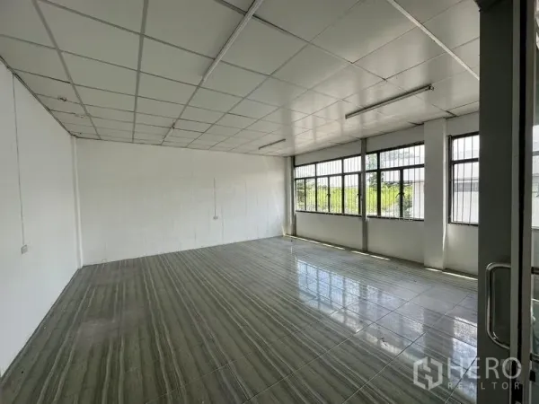 Warehouse for rent in Lam Luk Ka, Pathum Thani - Bright tiled office with large barred windows allowing natural light and a suspended ceiling.