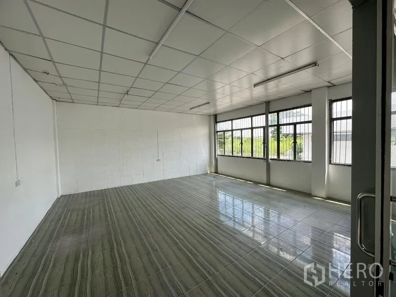 Warehouse for rent in Lam Luk Ka, Pathum Thani - Bright tiled office with large barred windows allowing natural light and a suspended ceiling.