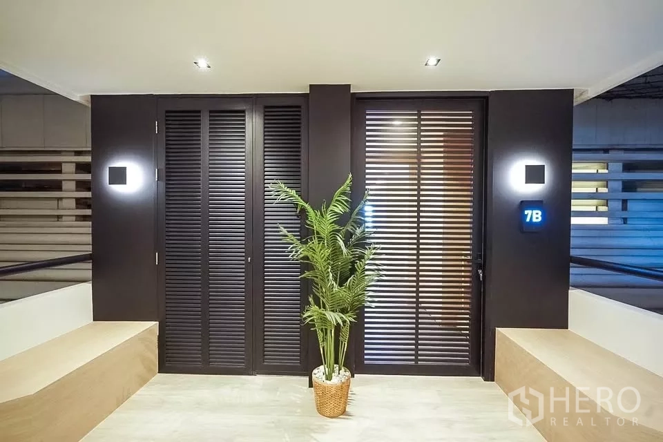 公寓 出租在Bang Phlat, Bangkok - 私密入户区，黑色百叶门、壁灯与绿植点缀。
