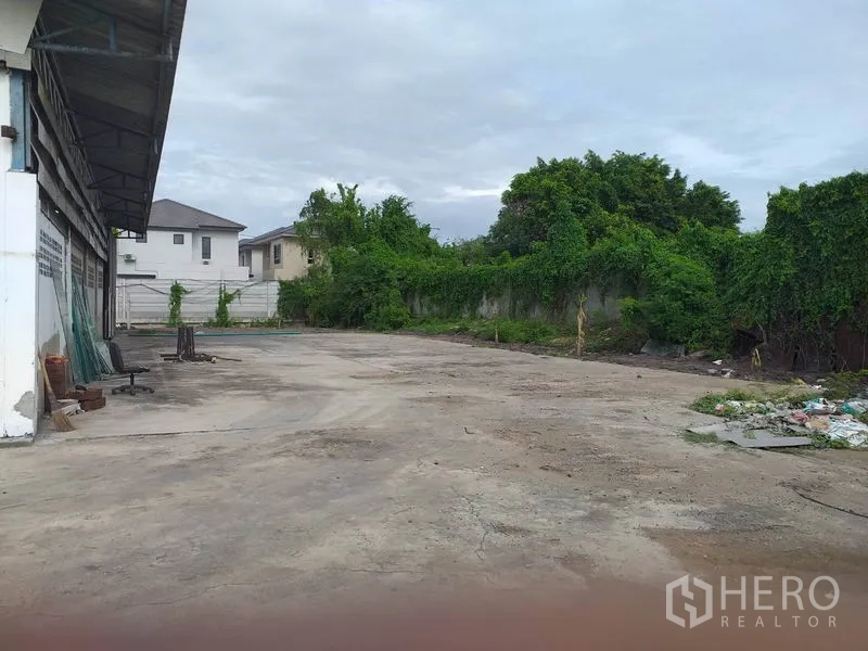 คลังสินค้า ให้เช่าในPak Kret, Nonthaburi - ลานด้านหลังพื้นคอนกรีต พร้อมกำแพงรั้วและพื้นที่สีเขียวรอบโกดัง