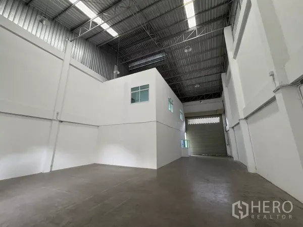 Factory for rent in Phra Samut Chedi, Samut Prakan - Warehouse hall with high steel roof and a mezzanine office block.