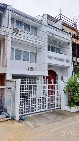联排别墅 出租在Watthana, Bangkok - 旺那那区三层白色联排别墅外观，带大门与阳台。