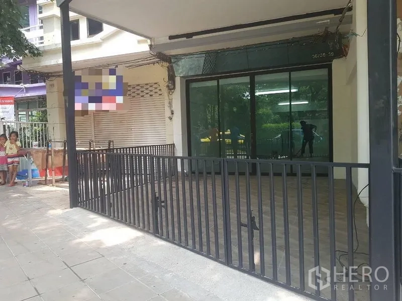 店屋 出租或出售在Lat Phrao, Bangkok - 带顶前庭与黑色金属栏杆，宽幅玻璃推拉门店面。