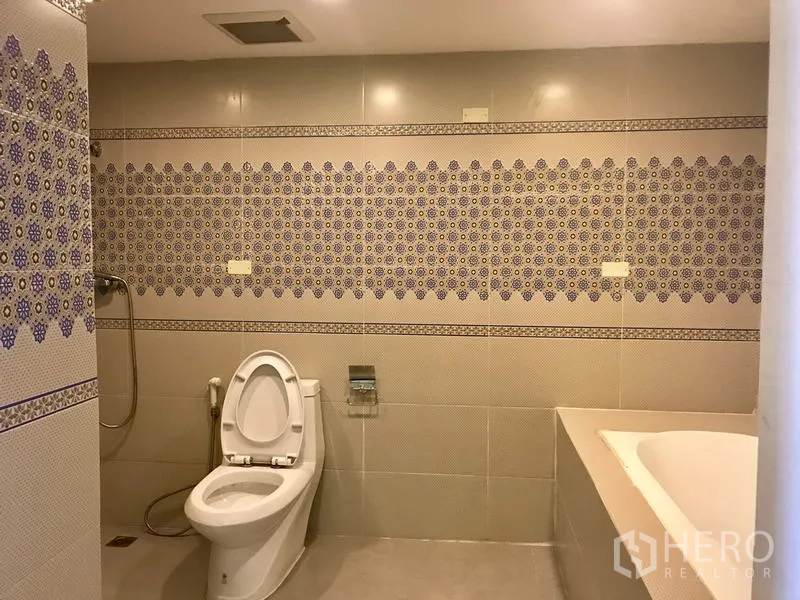 Condominium for rent in Watthana, Bangkok - Spacious living and dining room with chandelier, balcony doors and a brown sectional sofa.