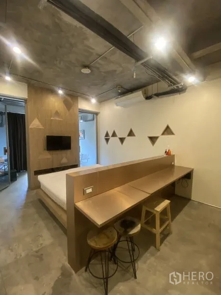 店屋 出租或出售在Khlong Toei, Bangkok - 卧室工作室，内置书桌、木质背景墙与工业风外露天花。