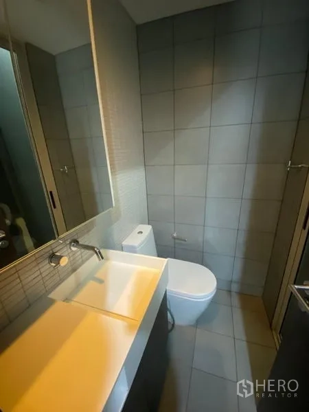 办公空间 出租在Phaya Thai, Bangkok - 现代化卫生间，挂墙式洗手台、大镜柜与灰色瓷砖墙面。