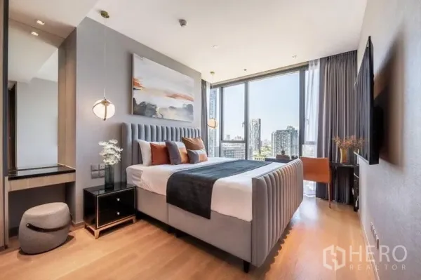 Condominium for rent in Khlong Toei, Bangkok - Bright primary bedroom with upholstered bed, pendant lights and floor‑to‑ceiling windows overlooking the Bangkok skyline.