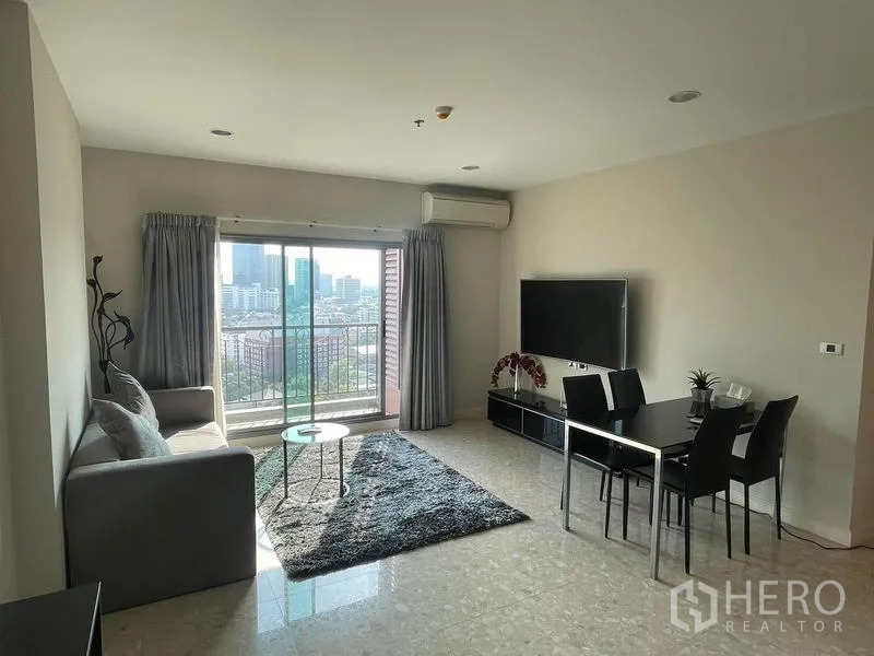 Condominium for sale in Khlong Toei, Bangkok - Open-plan living and dining area with sofa, balcony view and TV console.