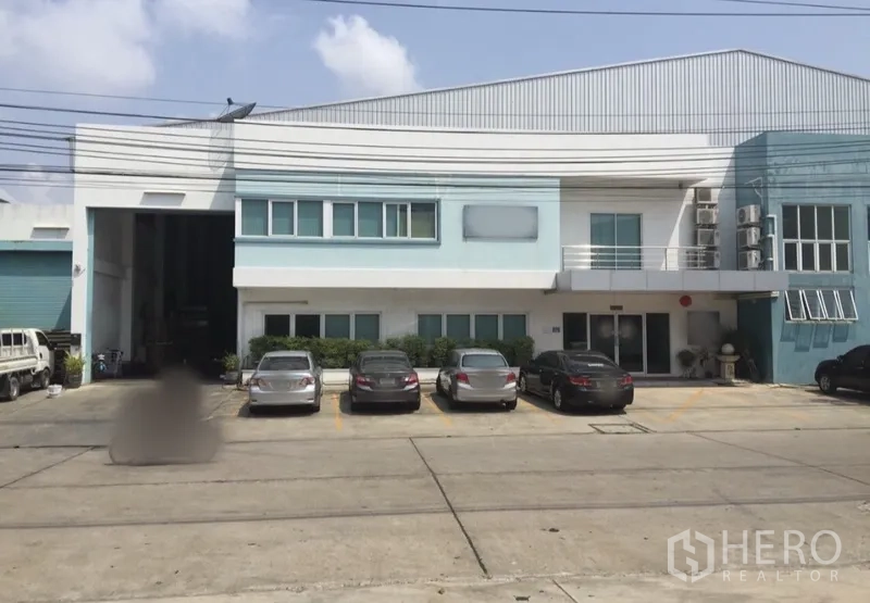 Factory for rent or sale in Bang Phli, Samut Prakan - Two-storey factory exterior in Bang Phli with front parking and a wide roller-shutter loading bay.