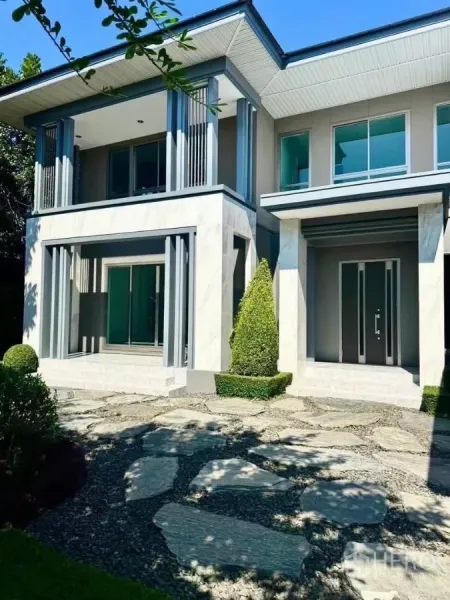 Detached House for rent in Lat Krabang, Bangkok - Front facade with large windows, balcony columns and a stepping-stone walkway.