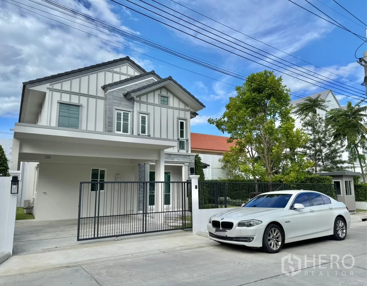 Detached House for rent in Bang Phli, Samut Prakan - Front facade with gated driveway, covered carport and modern windows.