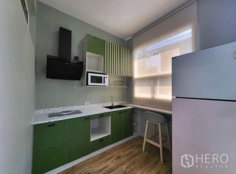 Townhouse for rent or sale - Modern kitchen with green cabinetry, cooktop, hood, microwave, sink, refrigerator and breakfast counter.