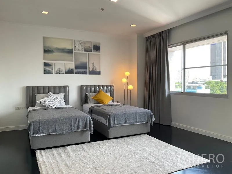 Apartment for rent in Sathon, Bangkok - Guest bedroom with twin beds, wall art and a big window.