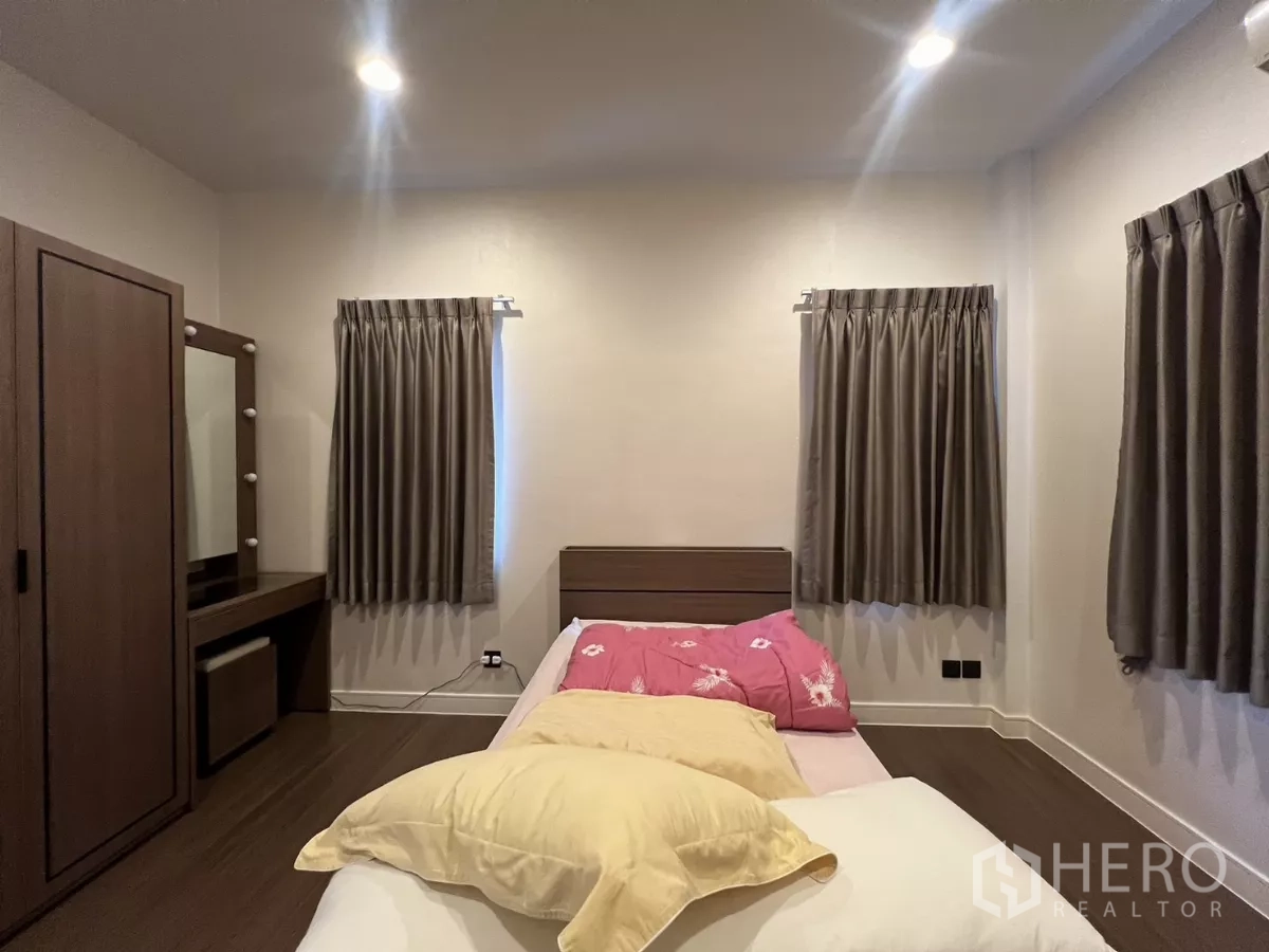 Detached House for rent in Bang Kapi, Bangkok - Secondary bedroom with dressing table and two curtained windows.