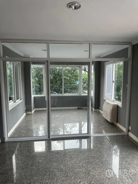 Townhouse for rent in Bang Kapi, Bangkok - Bright glass-partitioned room with corner windows looking out to greenery.