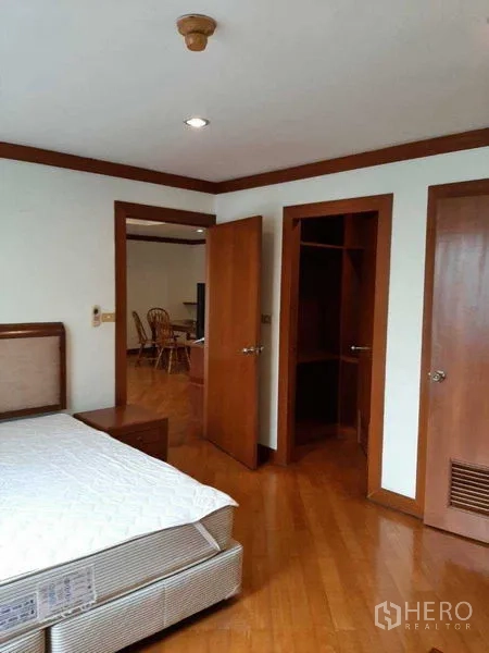 Apartment for rent in Watthana, Bangkok - Bedroom with bedframe, walk-in closet and wood doors.