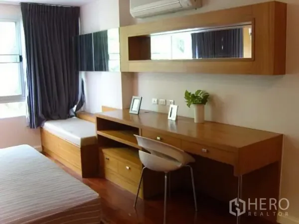 Condominium for rent in Watthana, Bangkok - Bedroom study corner with a long wooden work desk and overhead storage.