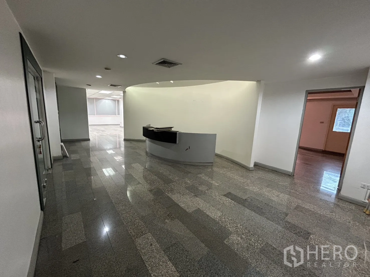 Office Space for rent in Khlong Toei, Bangkok - Reception lobby with a curved desk, downlights, and access to adjoining office rooms.