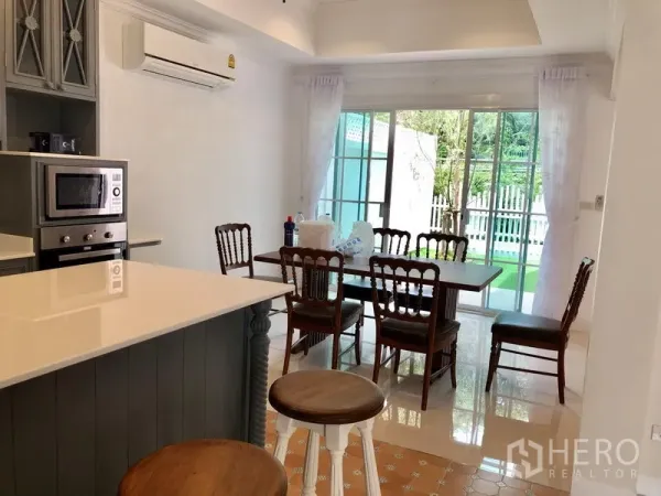 Detached House for rent in Mueang Samut Prakan, Samut Prakan - Bright dining area with wooden table and sliding glass doors opening to the garden.