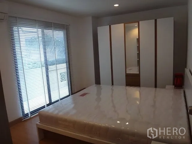 Condominium for rent in Bang Rak, Bangkok - Bedroom with sliding glass doors, venetian blinds, white wardrobe, and platform bed on wooden floors.