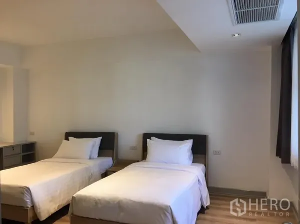 房间 出租在Khlong Toei, Bangkok - 第二卧室设两张单人床，木地板与遮光窗帘。