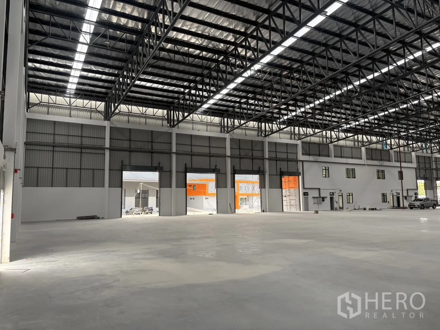 โรงงาน for rent in Bang Pakong, Chachoengsao - ภายในโกดังเห็นประตูม้วนหลายบานและส่วนสำนักงานด้านข้าง.