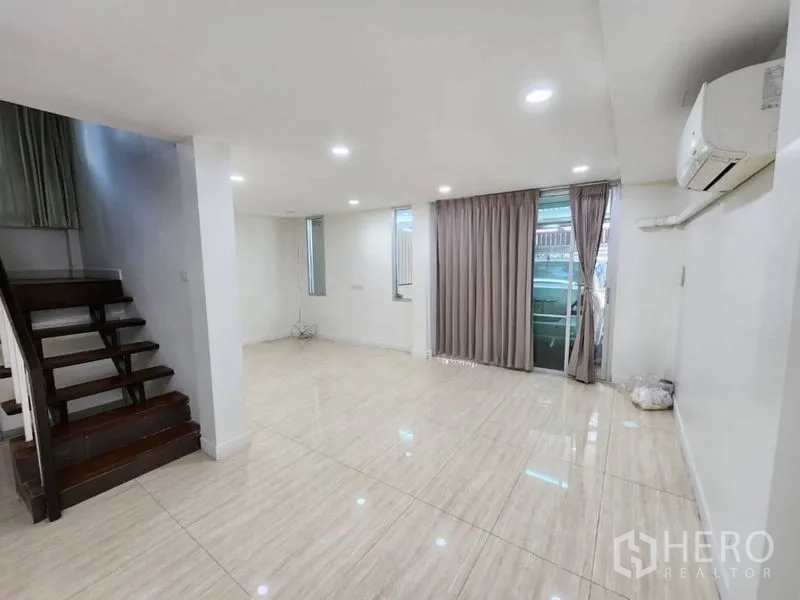 带办公室的家 出租在Khlong Toei, Bangkok - 明亮的开放式客厅，亮面地砖、筒灯、空调，旁有木楼梯与带窗帘的推拉门。