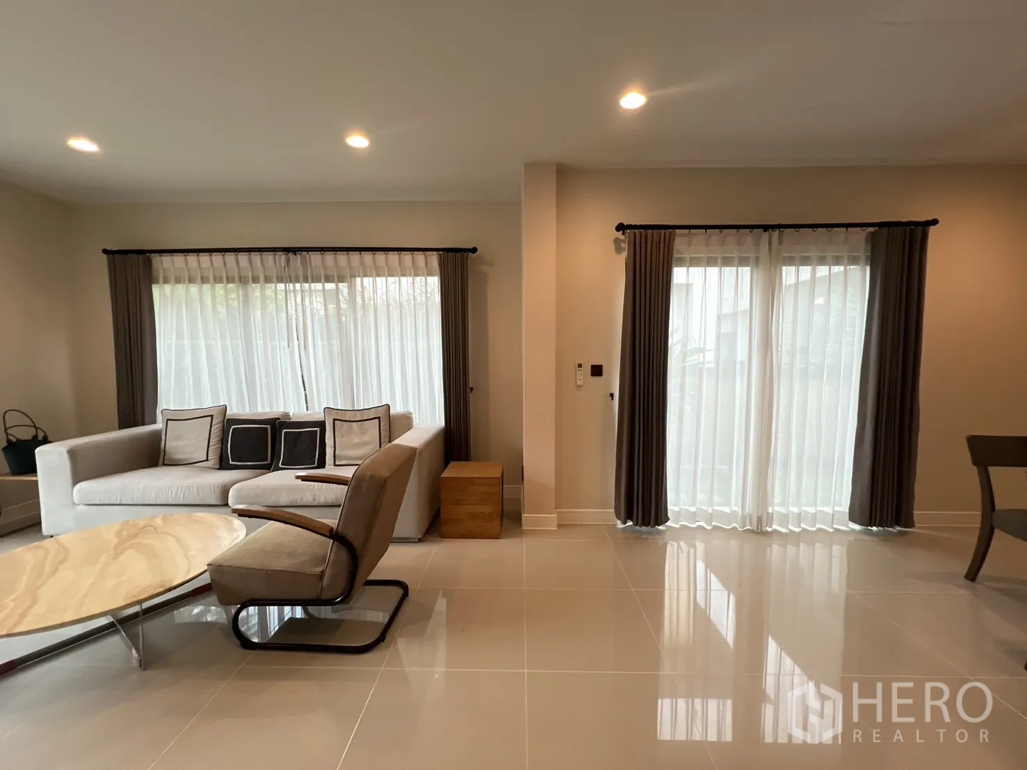 Detached House for rent in Bang Kapi, Bangkok - Living corner with large windows, sheer curtains, sofa and armchair.