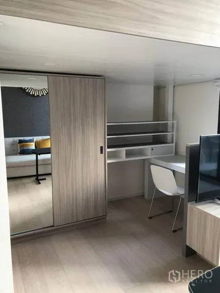 公寓 出售在Ratchathewi, Bangkok - 现代客厅内的书桌与置物架，紧邻带镜面滑门衣柜。