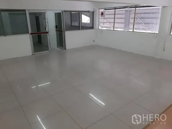 Office Space for rent in Khlong Toei, Bangkok - Open-plan office with glossy white tiles, large windows and glass-partitioned rooms.