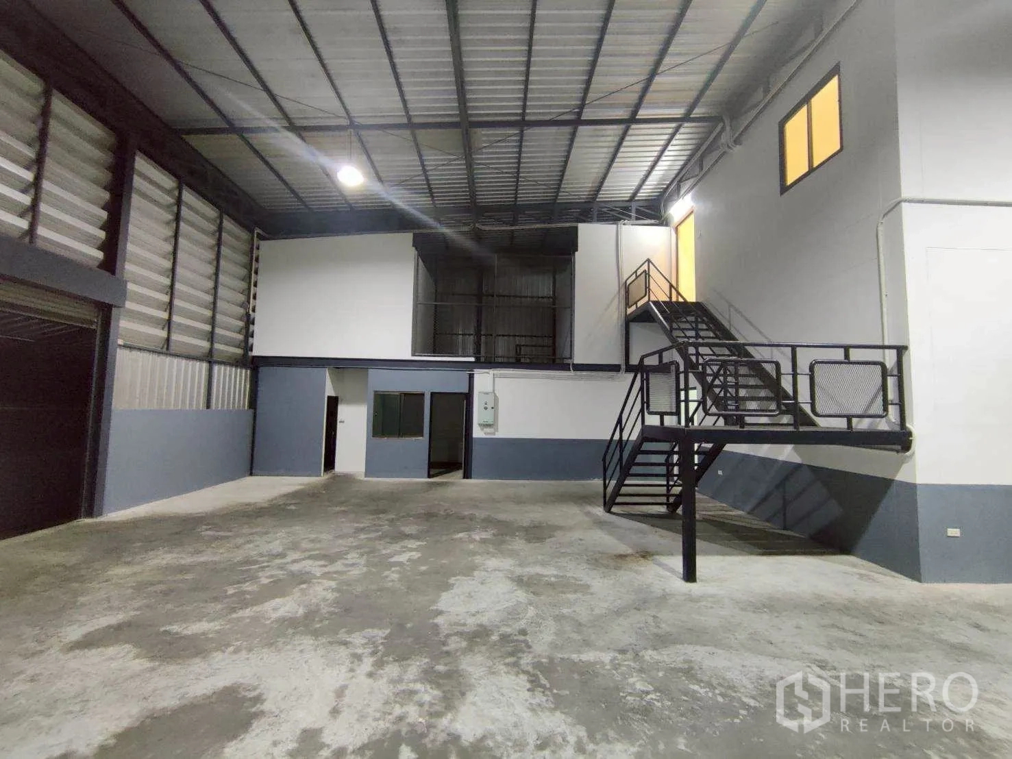 Warehouse for rent in Lam Luk Ka, Pathum Thani - Interior angle highlighting a metal staircase leading to mezzanine offices.