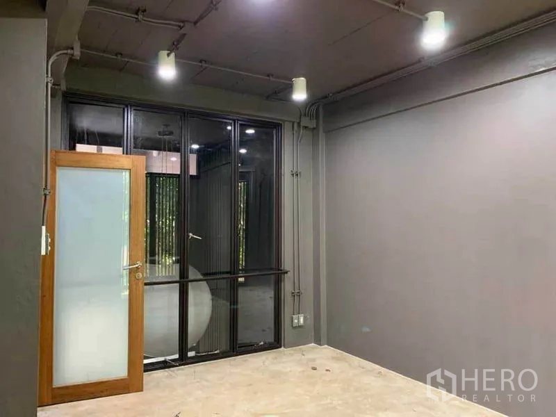 Home Office for rent in Huai Khwang, Bangkok - Empty gray room with frosted glass door and black-framed windows.