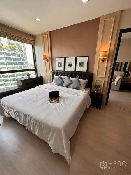 Condominium for rent or sale in Khlong Toei, Bangkok - Bedroom with large window, city view and doorway leading back to the living area.