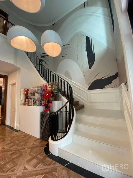 Detached House for sale in Saphan Sung, Bangkok - Grand foyer with a curved staircase, abstract mural and pendant lights.
