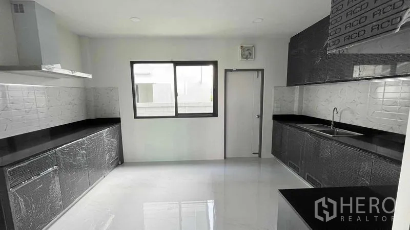 Detached House for sale in Bang Phli, Samut Prakan - Alternate view of the kitchen showing twin counters, cooker hood and rear door.