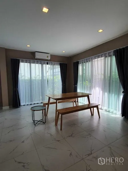 Detached House for rent in Khlong Luang, Pathum Thani - Corner dining space with wooden table and benches beside wraparound windows.