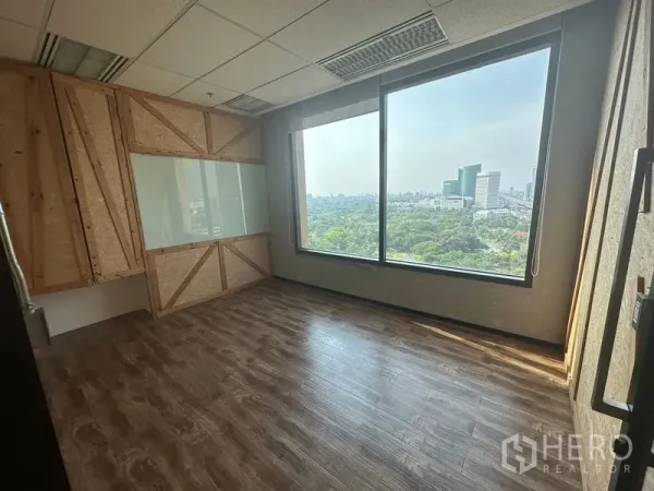 Office Space for rent in Chatuchak, Bangkok - Private office featuring an OSB accent wall, whiteboard, and floor-to-ceiling window facing park greenery.