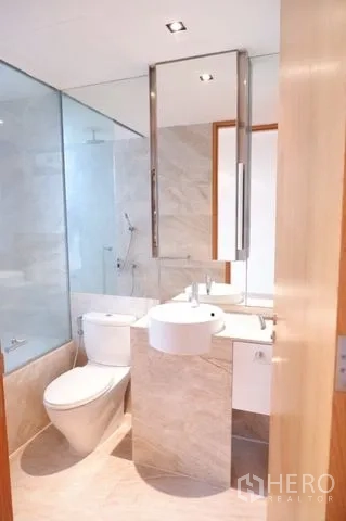 Condominium for sale in Sathon, Bangkok - Contemporary bathroom with large mirror, glass-enclosed shower, and marble tiles.