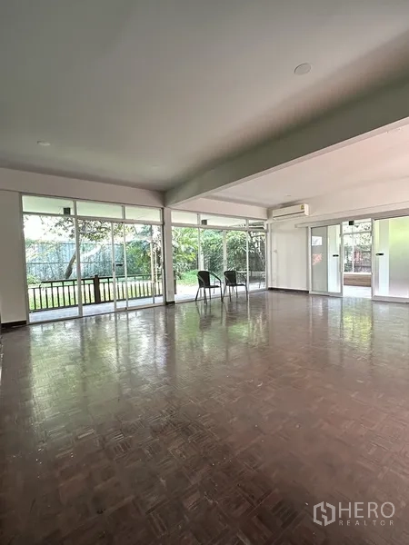 独立式住宅 出租在Khlong Toei, Bangkok - 明亮起居区，大面积窗墙观景花园，摆放两把椅子