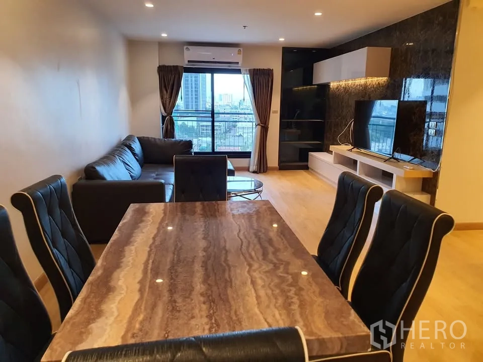 Condominium for rent in Watthana, Bangkok - Open-plan living and dining with marble-top table, black chairs, sofa, balcony view and media wall.