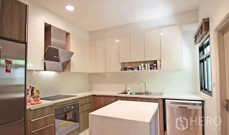 Detached House for rent in Bang Khae, Bangkok - Modern U-shaped kitchen with island, built-in oven and ample cabinetry.