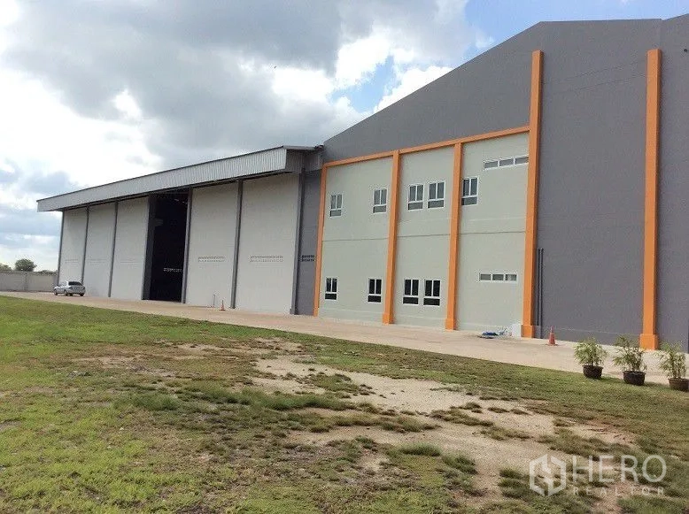 โรงงาน ขายในBang Sao Thong, Samut Prakan - ภายนอกโกดังมีประตูม้วนสูงและเสาแนวสีส้ม.