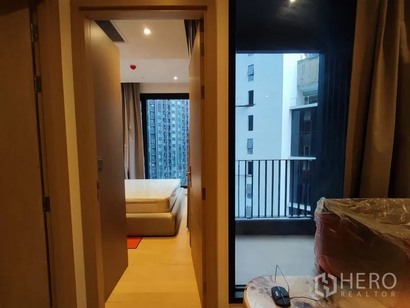 公寓 出租在Din Daeng, Bangkok - 过道望向卧室与带栏杆的阳台，可见周边高楼。