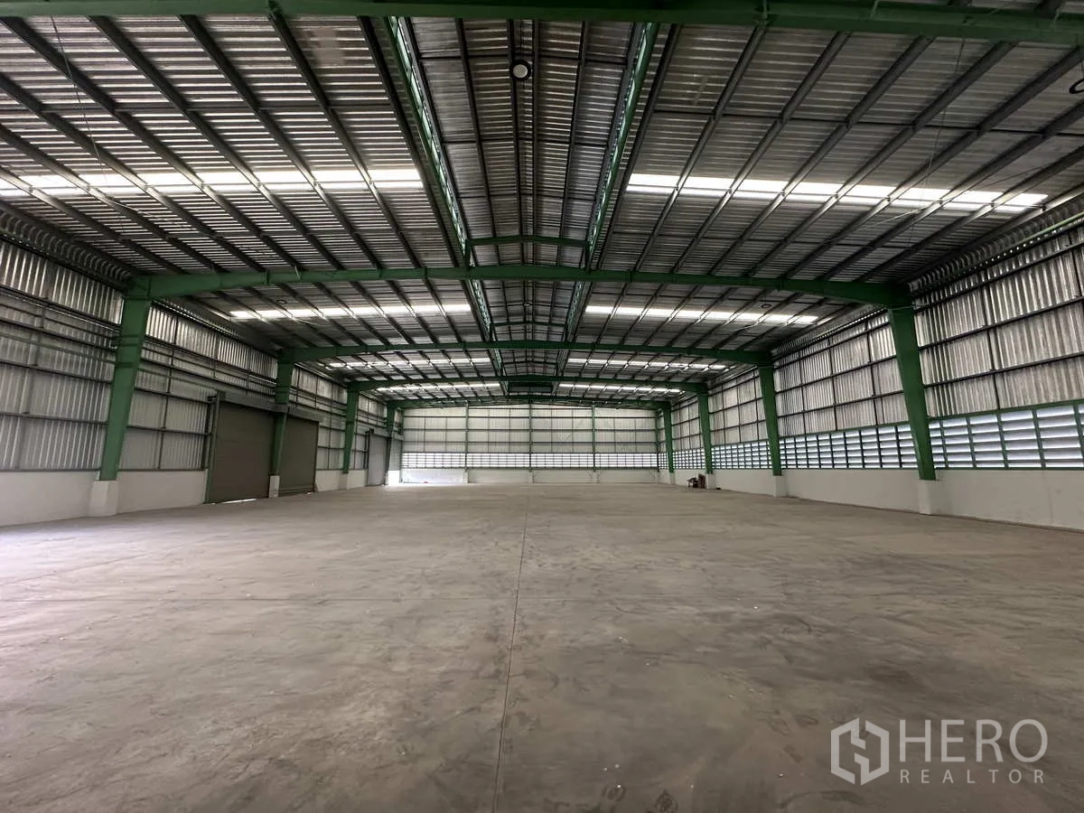 โรงงาน ให้เช่าในMueang Samut Prakan, Samut Prakan - ภายในคลังสินค้าโล่ง มองไปยังผนังด้านท้าย พร้อมประตูม้วนหลายบาน ไม่มีเสากลาง