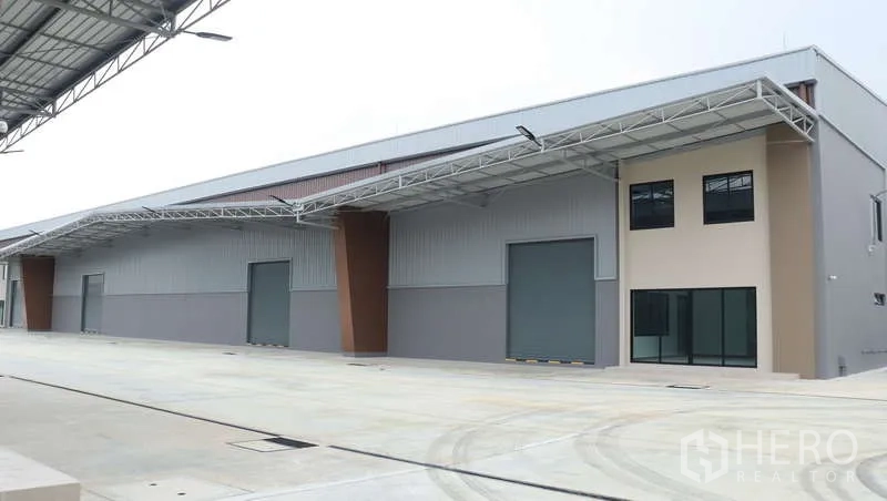 Warehouse for rent in Sam Phran, Nakhon Pathom - Long warehouse block with multiple docks beneath deep canopies and glass‑fronted offices.