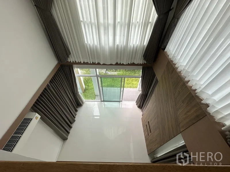 Detached House for sale in Lam Luk Ka, Pathum Thani - View from the mezzanine down into the double-height living room and garden.