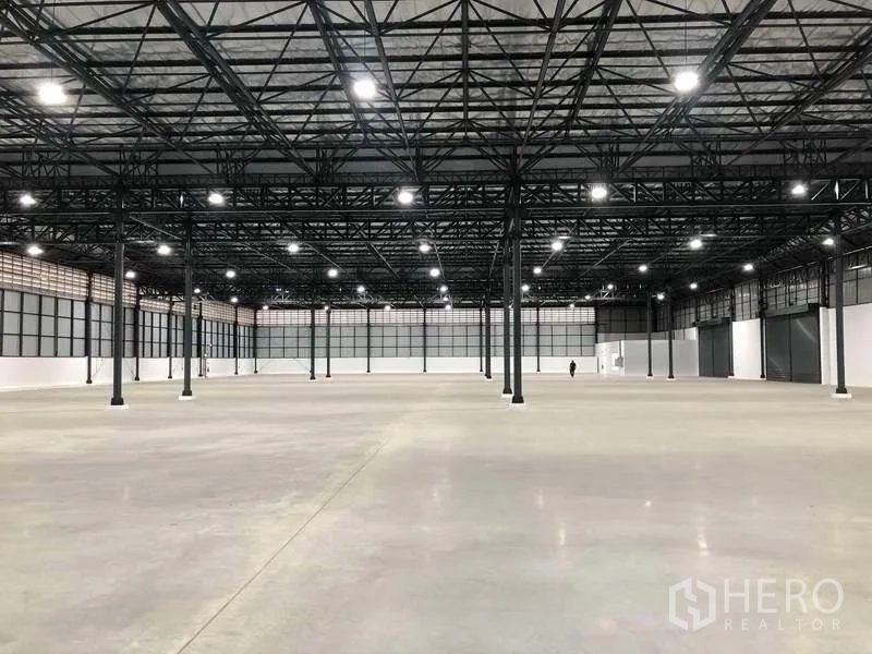 Factory for rent in Bang Sao Thong, Samut Prakan - Large clear warehouse area with grid lighting and steel columns.