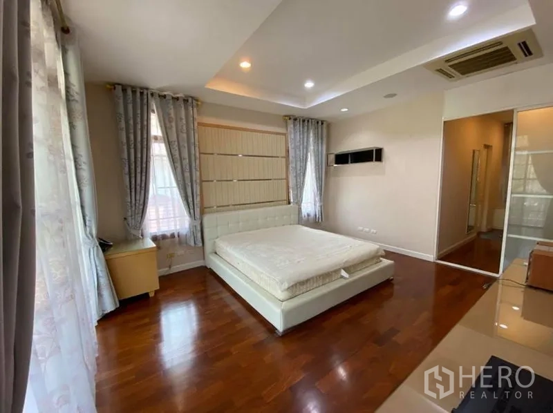 Detached House for rent in Bang Phli, Samut Prakan - Primary bedroom with recessed ceiling, large windows, hardwood floors and sliding wardrobe.